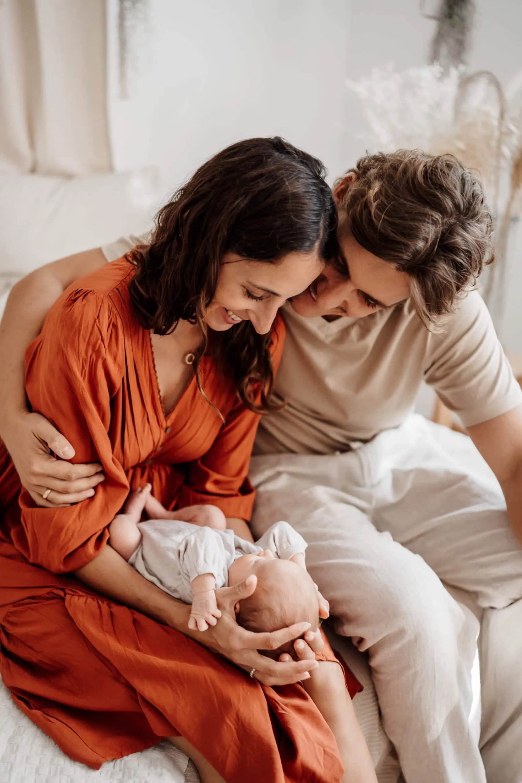 Familienfoto mit Mama und Papa und Neugeborenem sitzend auf dem Bett im Fotostudio in Rangendingen bei Monja Drössel von Fotografie Herzseeligkeit