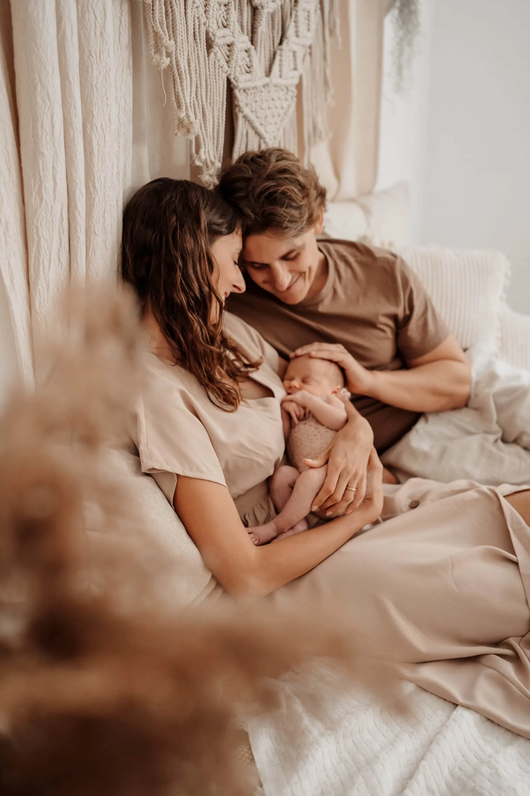 Familienfoto mit Mama und Papa und Neugeborenem sitzend auf dem Bett im Fotostudio in Rangendingen bei Monja Drössel von Fotografie Herzseeligkeit