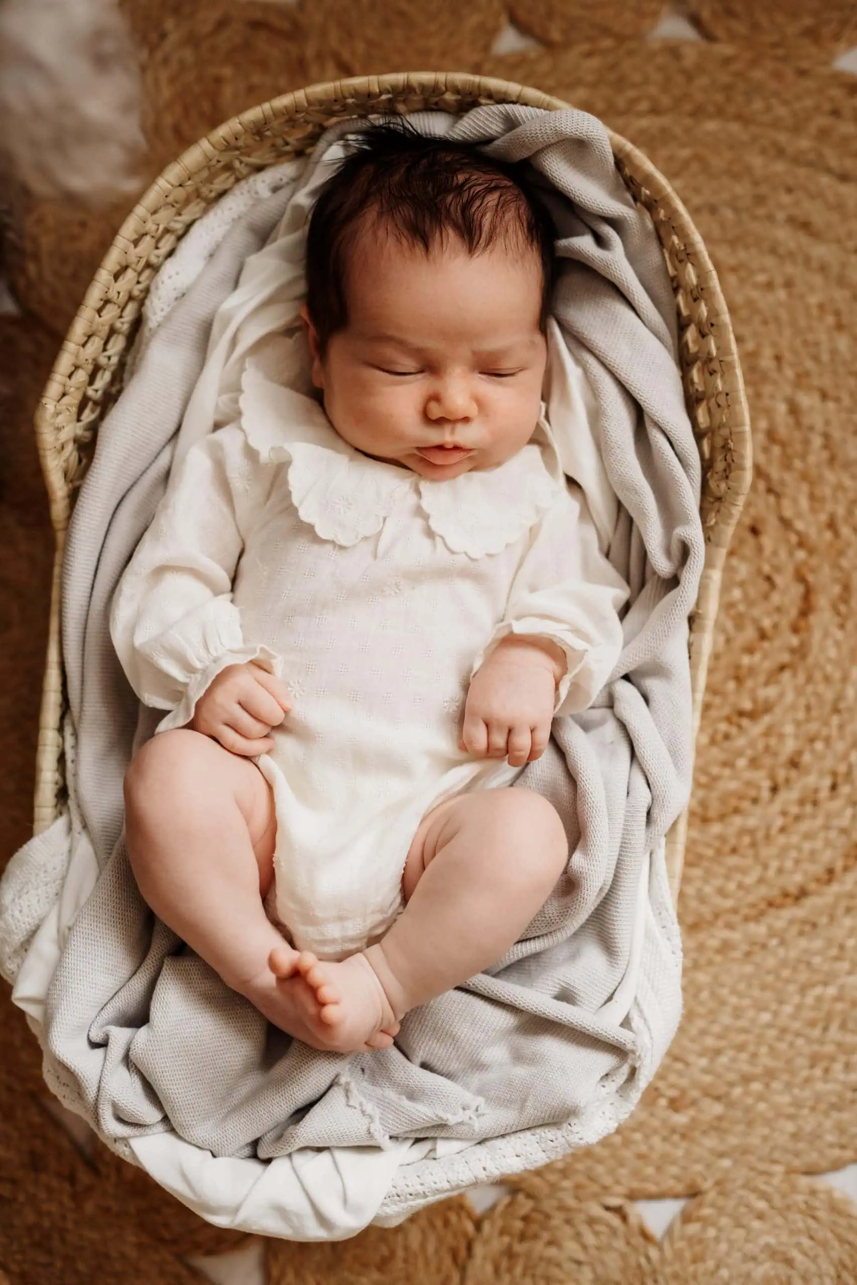 Neugeborenes Baby liegend eingekuschelt im Body aus dem Kundenkleiderschrank im Fotostudio von Monja Drössel in der Nähe von Tübingen