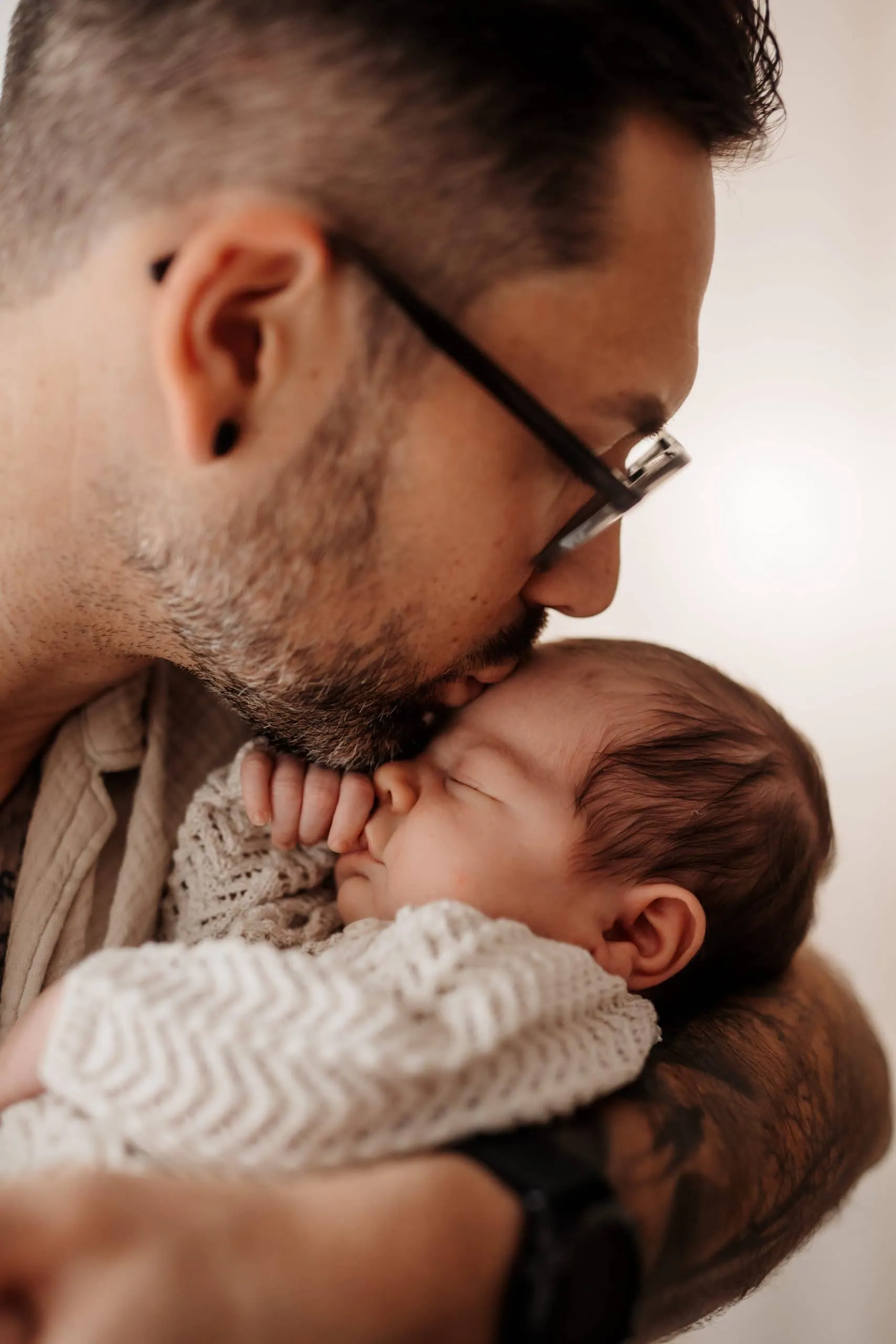 Papa küsst neugeborenes Baby sanft und hält es im Arm Familienfotografin Monja Drössel fotografiert