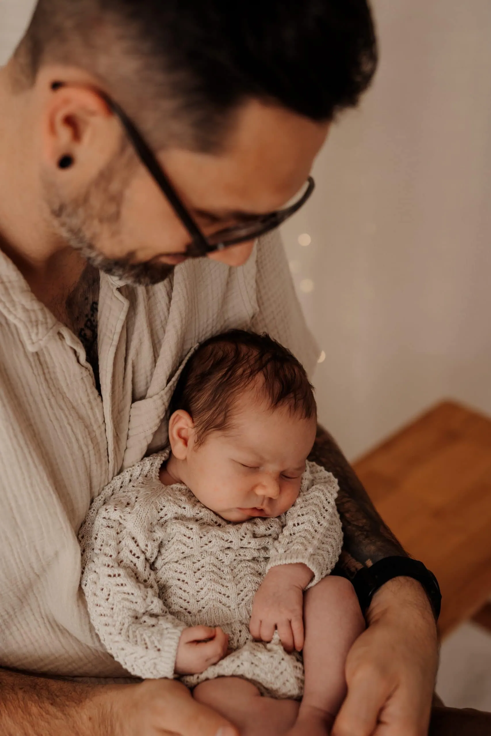 Baby auf Papas Arm Der Papa hält sein Neugeborenes ganz sanft und trägt Kleidung aus dem Kundenkleiderschrank von Monja Drössel