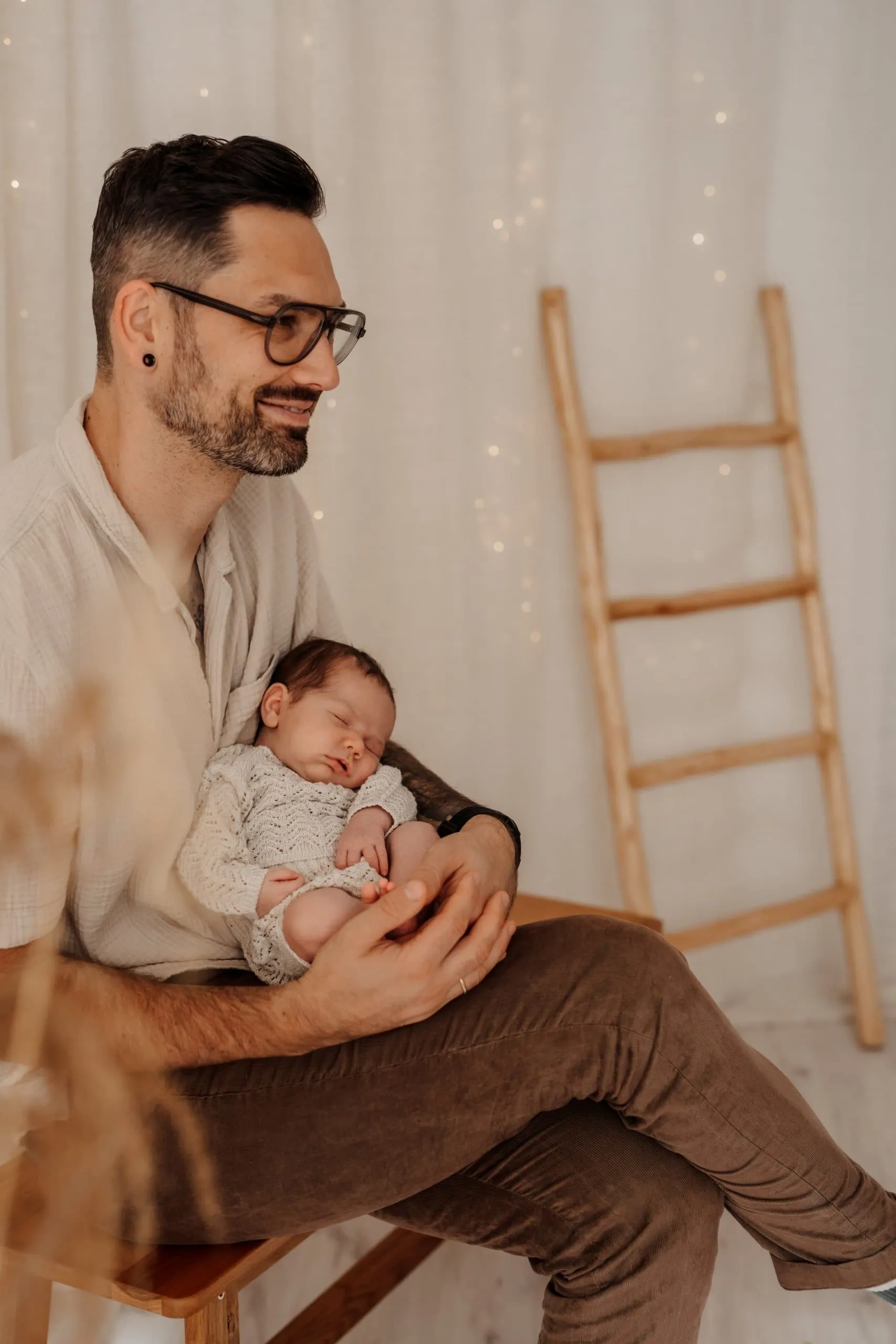 Baby auf Papas Arm Der Papa hält sein Neugeborenes ganz sanft und trägt Kleidung aus dem Kundenkleiderschrank von Monja Drössel