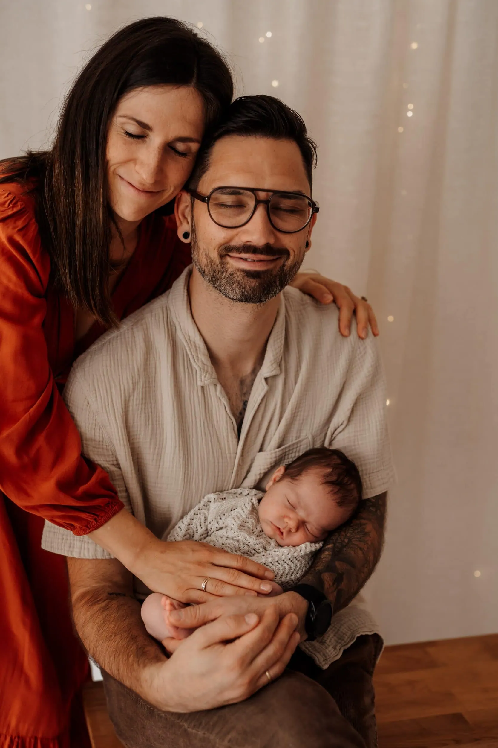 Baby wird von Papa gehalten Mama umarmt Neugeborenes Fotografin Monja Drössel macht Neugeborenenfotos