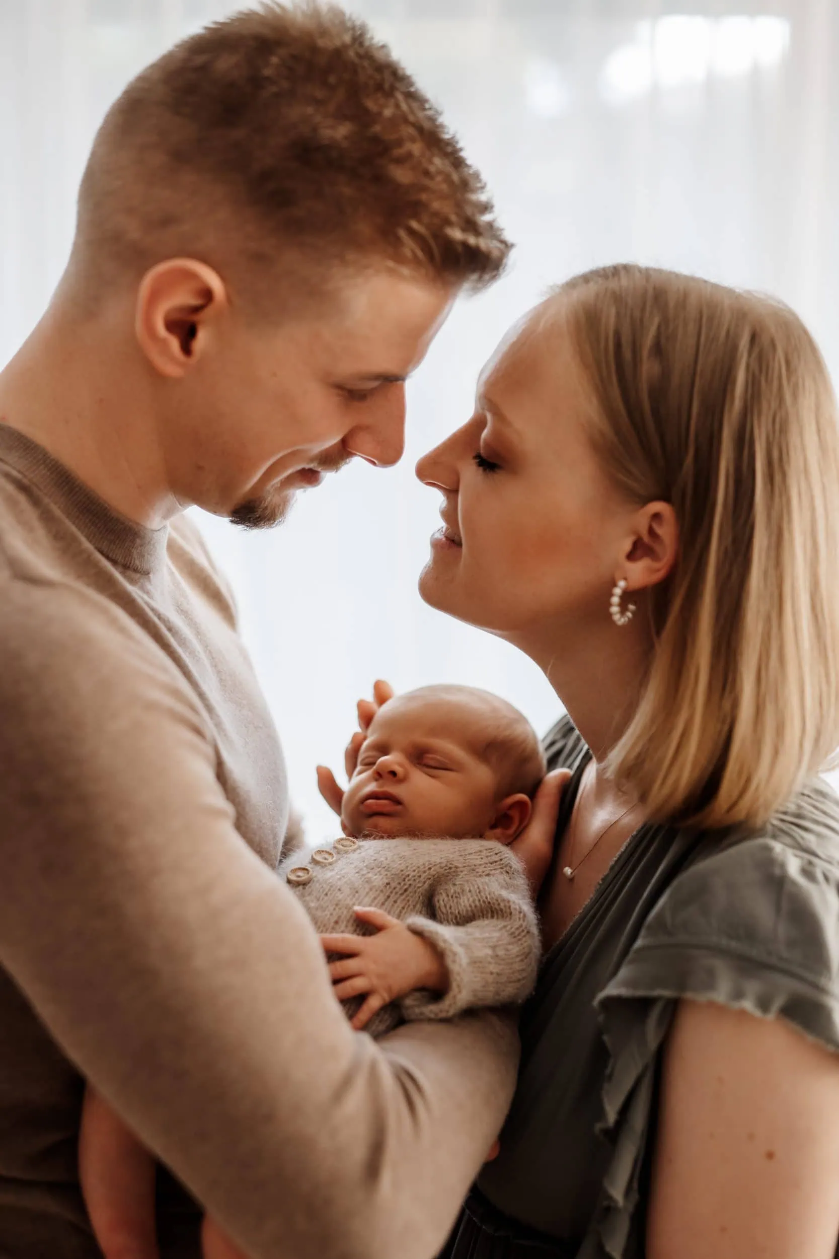 Mama und Papa halten ihr Neugeborenes sie fühlen sich geborgen und nutzen den Rundum Service mit Kundenkleiderschrank von Fotografin Monja Drössel
