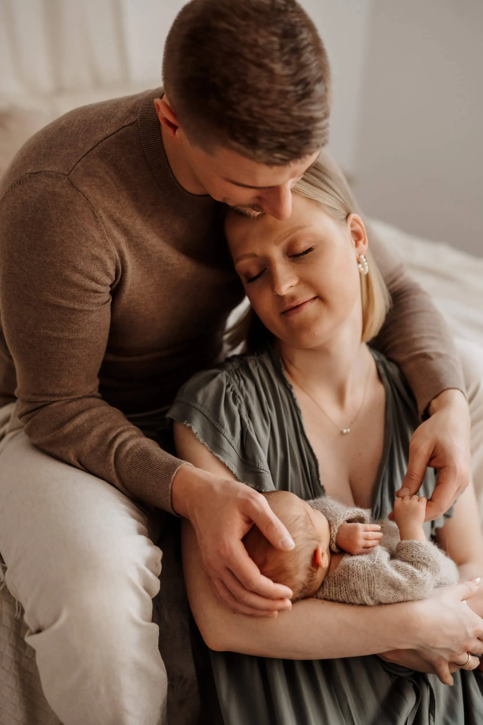 Neugeborenes Baby liegt in Mamas Arm und Papa streichelt sanft die Familie wird fotografiert von Monja Drössel der Familienfotografin nähe Hechingen